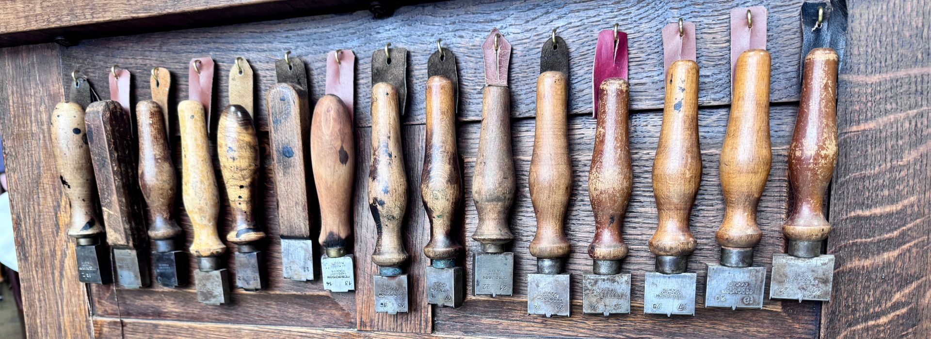 Alignement d'outils anciens à manche bois sur l'établi de l'atelier