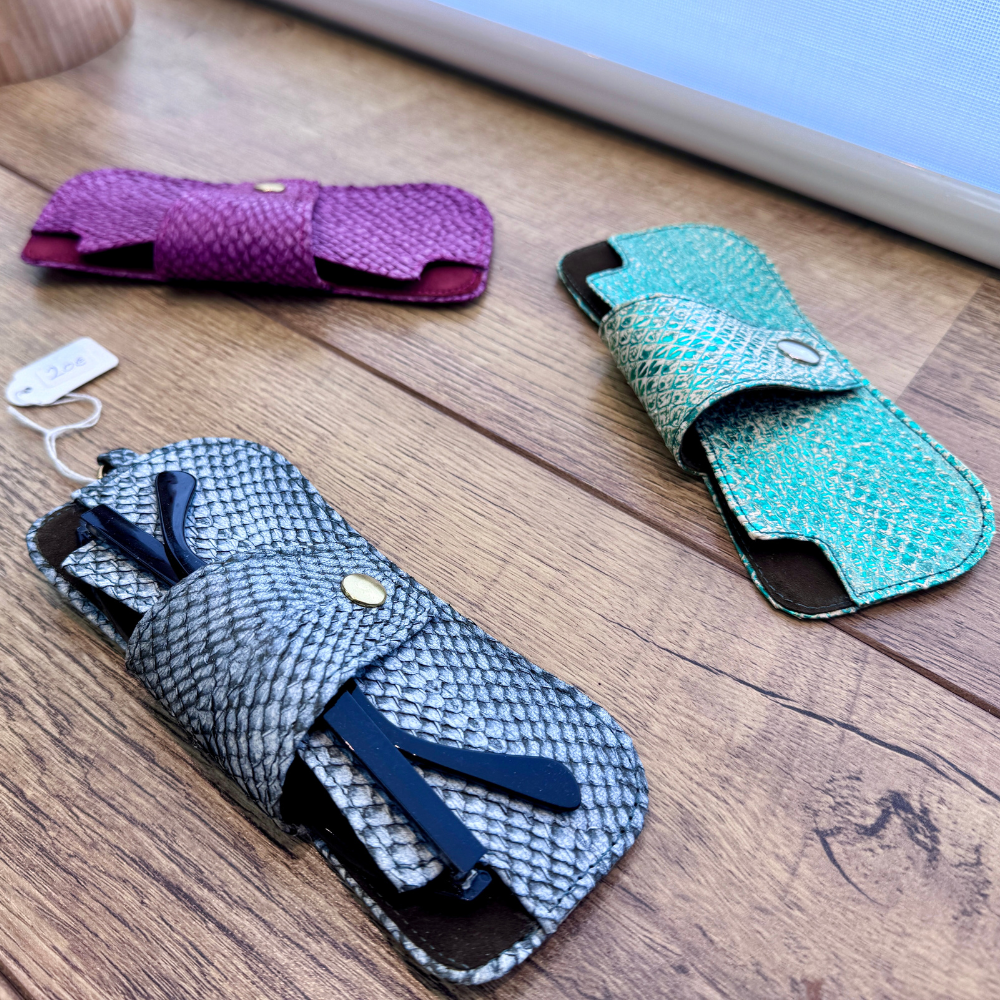 Porte-lunettes en cuir façonnés à l'atelier, posés sur un plan en bois
